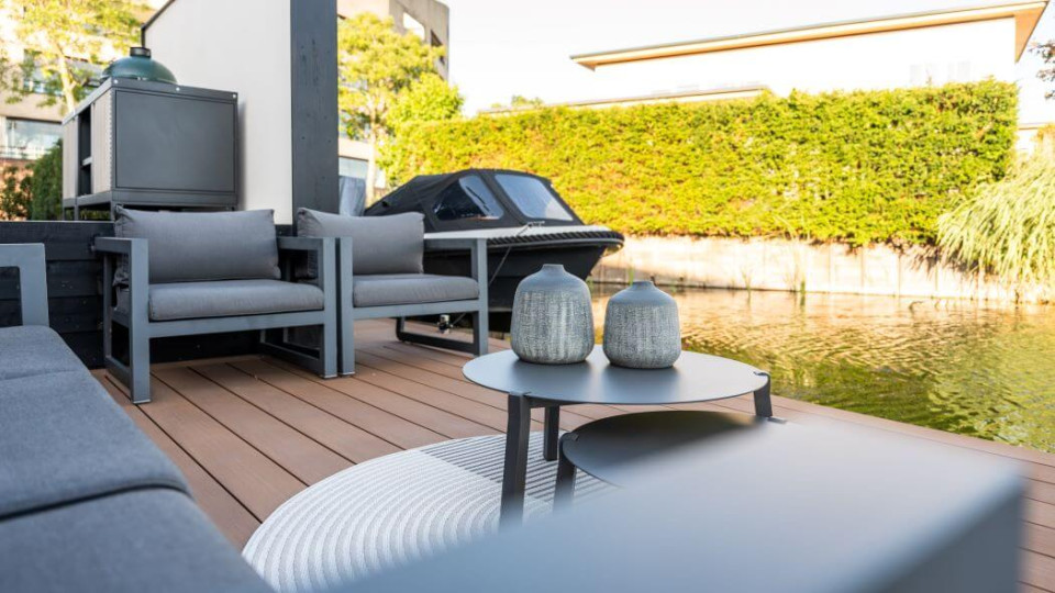 Loungeterras in een moderne achtertuin aan het water, met een aanlegplek voor de boot en comfortabele zitplekken