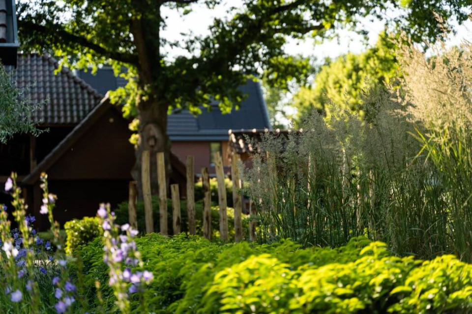 Beplantingsplan met siergrassen, gecombineerd met robuuste Robinia houten palen die een natuurlijke en stijlvolle structuur aan de tuin geven.
