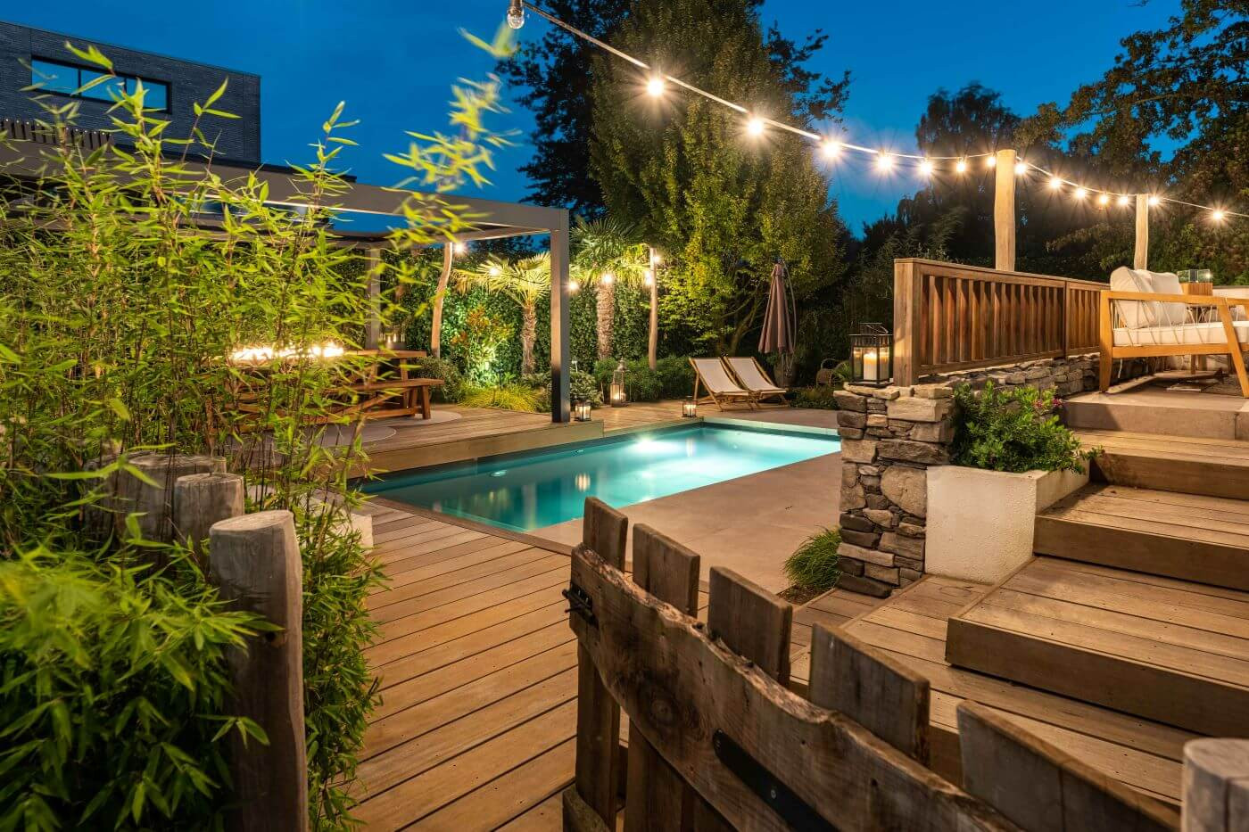 : Bamboehaag en tropische planten cre&euml;ren privacy in een luxe Balinese achtertuin met zwembad.